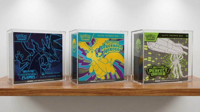 Three Pokemon Center ETBs stored in clear acrylic display cases on wooden shelf