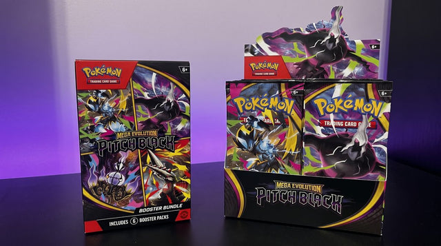 A Pokemon Pitch Black Booster Bundle beside an open Pitch Black Booster Box display on a black desk