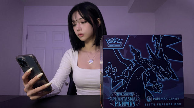 A Phantasmal Flames Pokemon Center Elite Trainer Box on a desk while Evol Vault content host Alice checks her phone
