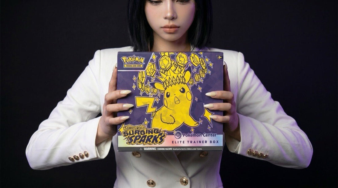 Pokemon Surging Sparks Pokemon Center Elite Trainer Box held by the Evol Vault content host in editorial product photography on a dark studio backdrop
